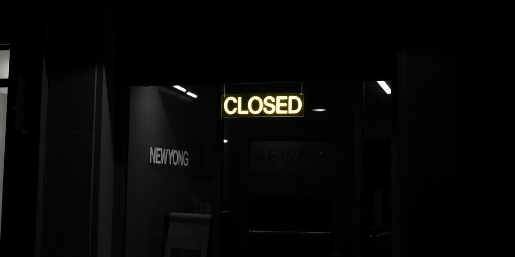 new york city closed small business store front with a neon sign that says closed